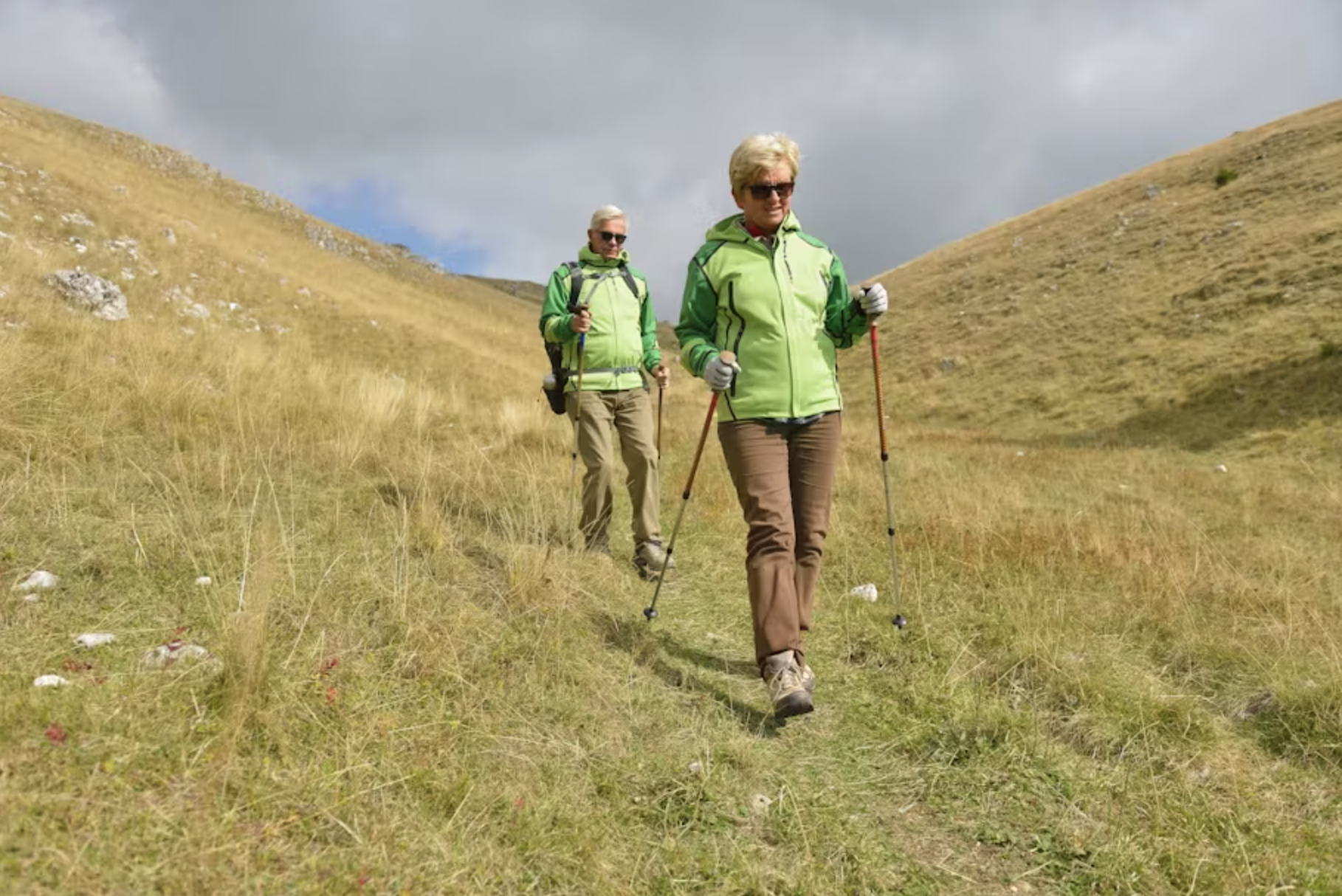 Two older hikers walking along a mountain trail